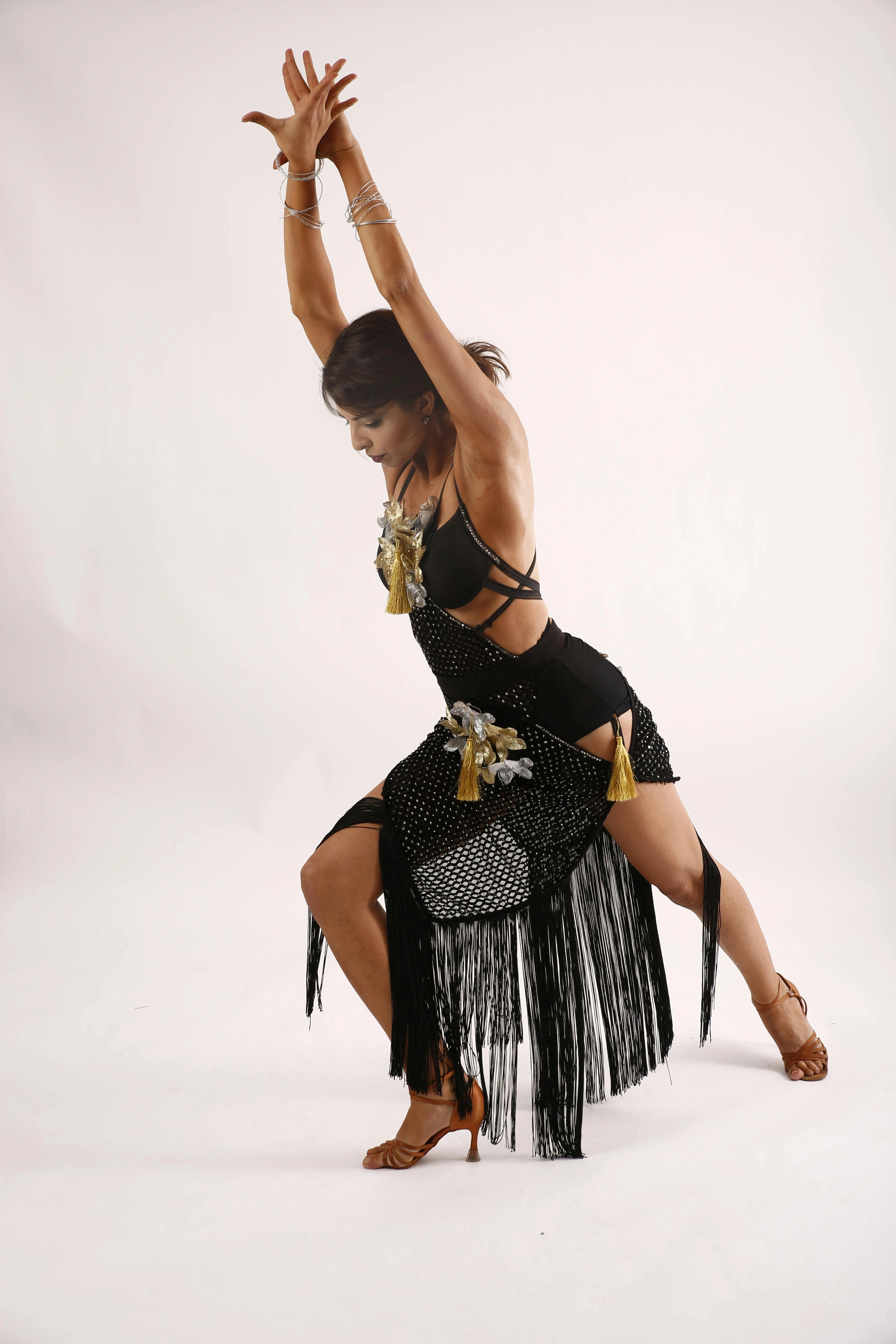 Fashion model in black fringed dance outfit posing in studio